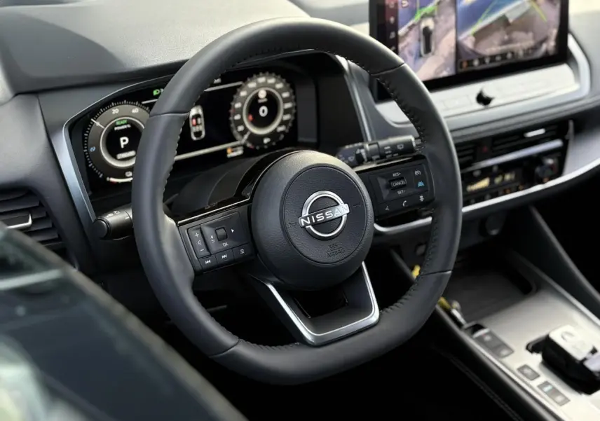 Vue rapprochée du volant noir et du tableau de bord numérique du Nissan Qashqai III e-Power 2025, avec écran tactile central.