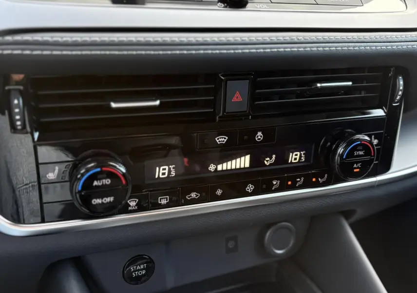 Détail du tableau de bord noir du Nissan Qashqai blanc nacré 2025, affichage numérique de la climatisation bi-zone.