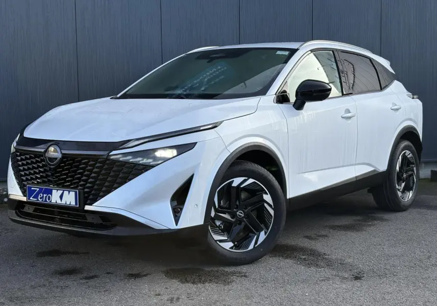 Nissan Qashqai blanc nacré en 3/4 avant droit, avec calandre noire et jantes alliage bicolores distinctives.