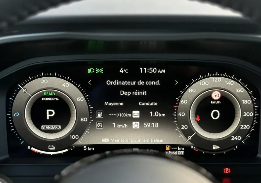 Tableau de bord numérique du Nissan Qashqai blanc nacré, affichage central des données de conduite à 11h50.