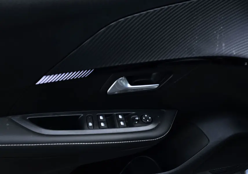 Détail de la porte intérieure côté conducteur de la Peugeot 208 grise, avec commandes des vitres et poignée argentée.