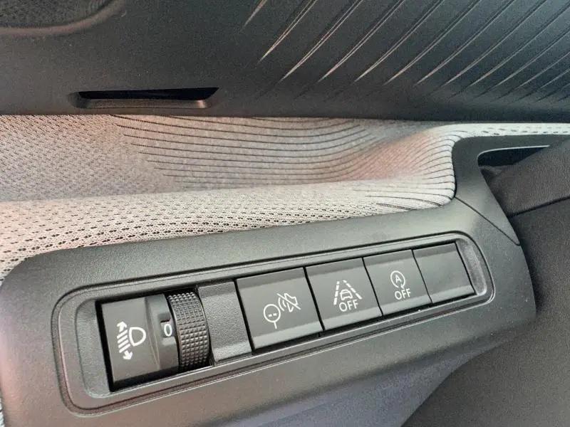 Gros plan sur les commandes d'assistance à la conduite dans une Citroën C3 1.2 Turbo noire, avec tissu clair en arrière-plan.