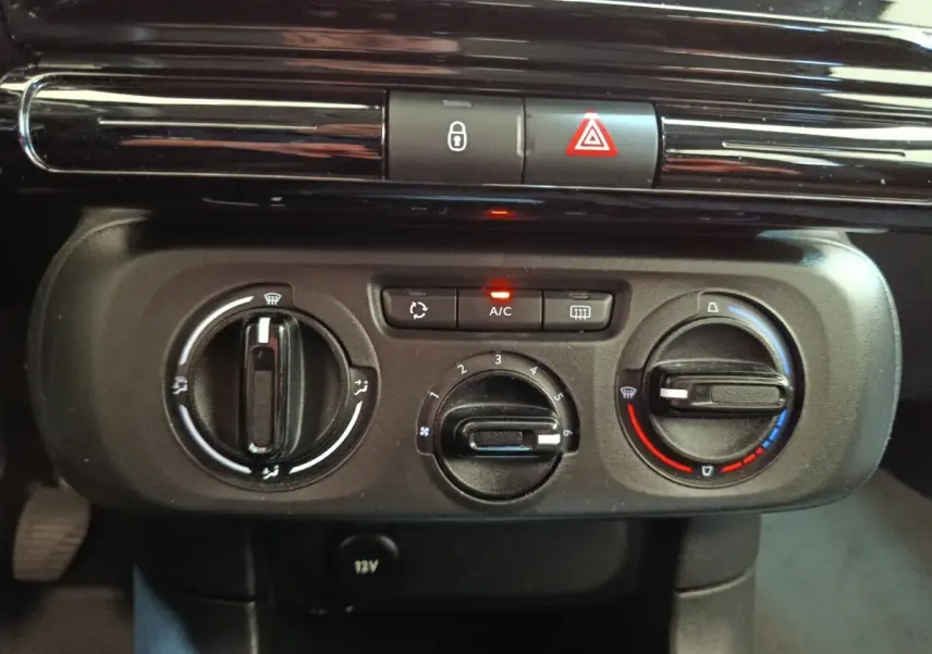 Vue rapprochée du tableau de bord central de la Citroën C3 blanche, montrant les commandes de climatisation et les boutons de sécurité.