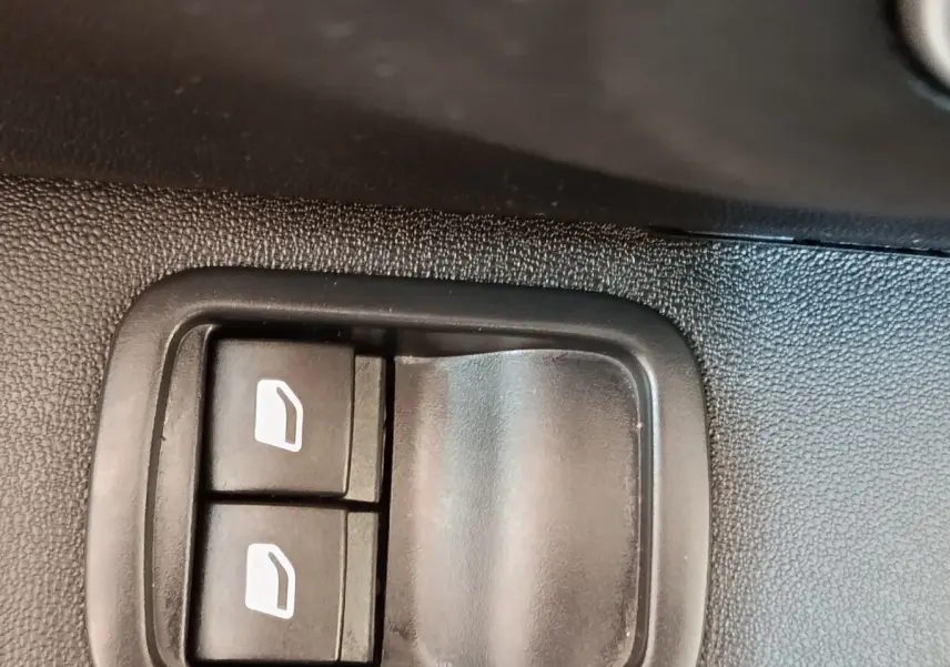 Gros plan sur les commandes des vitres électriques côté conducteur d'une Citroën C3 blanche, intérieur noir.