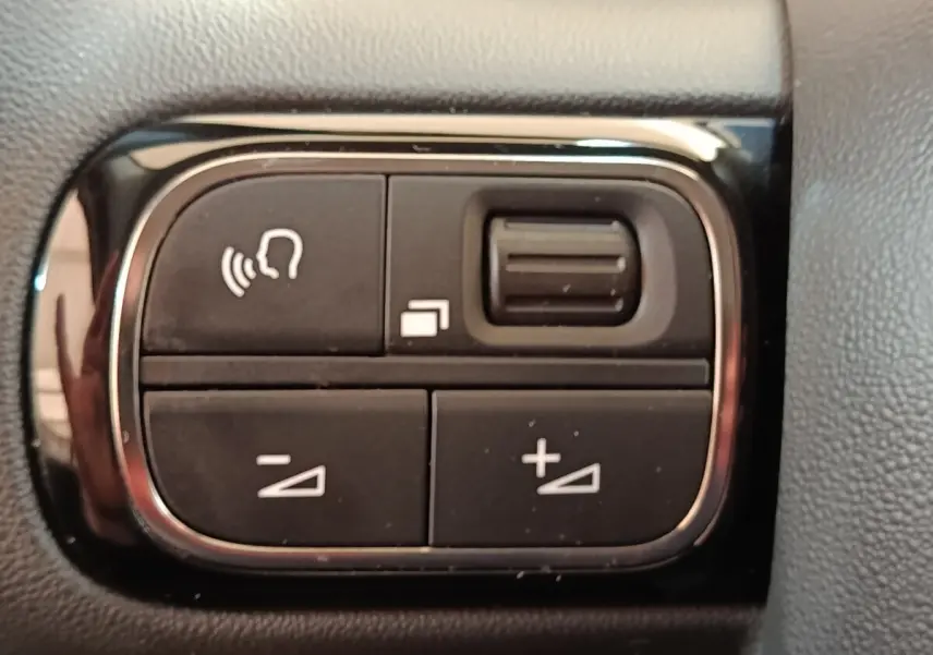 Gros plan sur les commandes noires du volant multifonctions de la Citroën C3 blanche, version BlueHDi 100 S&S BVM Feel.