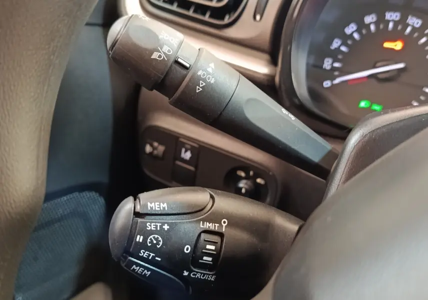 Gros plan sur les commandes de régulateur de vitesse et phares du tableau de bord d’une Citroën C3 blanche 2021.
