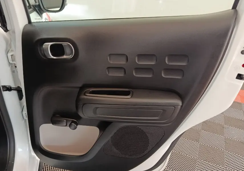 Vue intérieure de la porte arrière gauche blanche d'une Citroën C3 2021 avec poignée et haut-parleur intégrés.
