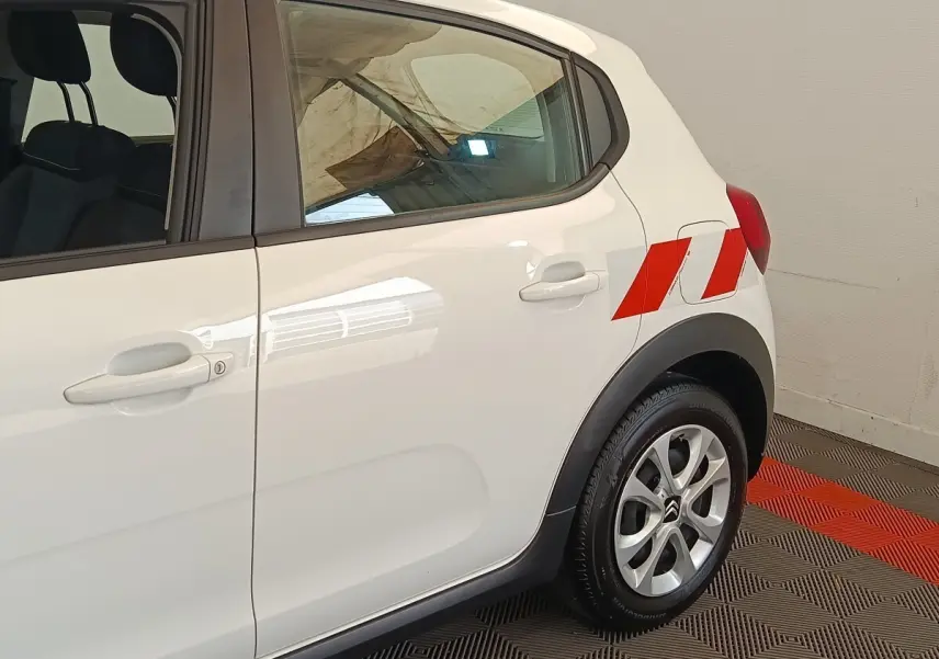 Vue latérale droite d'une Citroën C3 blanche 2021 avec marquages rouges sur l'aile arrière et jantes alliage.