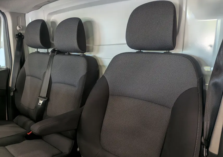 Vue rapprochée des sièges avant en tissu gris foncé du Renault Trafic Fourgon Blanc Minéral 2024, version Advance.