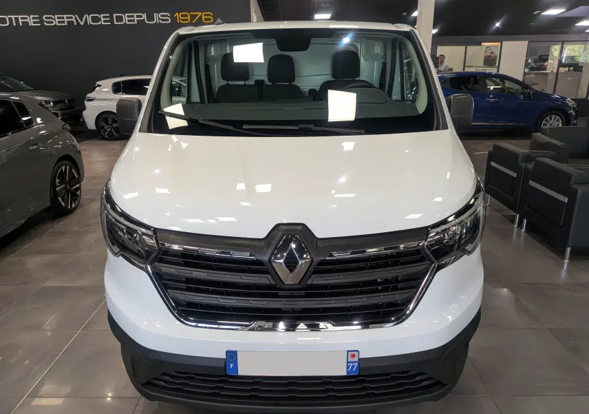 Vue frontale d’un Renault Trafic Fourgon blanc minéral 2024, avec calandre noire et logo Renault bien visible.