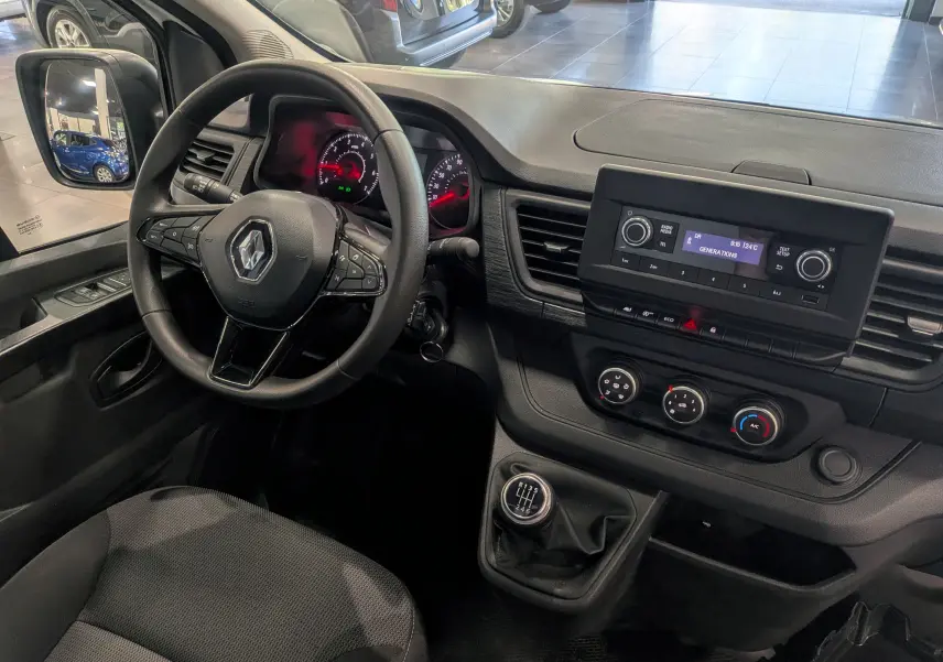 Vue intérieure côté conducteur du Renault Trafic Fourgon blanc, montrant le volant multifonction, tableau de bord et levier de vitesses manuel.