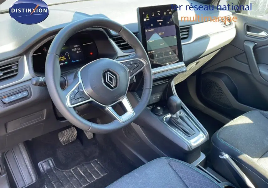 Vue intérieure côté conducteur du Renault Captur E-Tech hybride 2025, avec volant multifonction et écran tactile vertical.