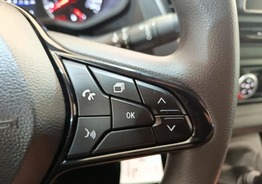 Gros plan sur les commandes multifonctions noires du volant du Renault Trafic Fourgon blanc, version 2023.
