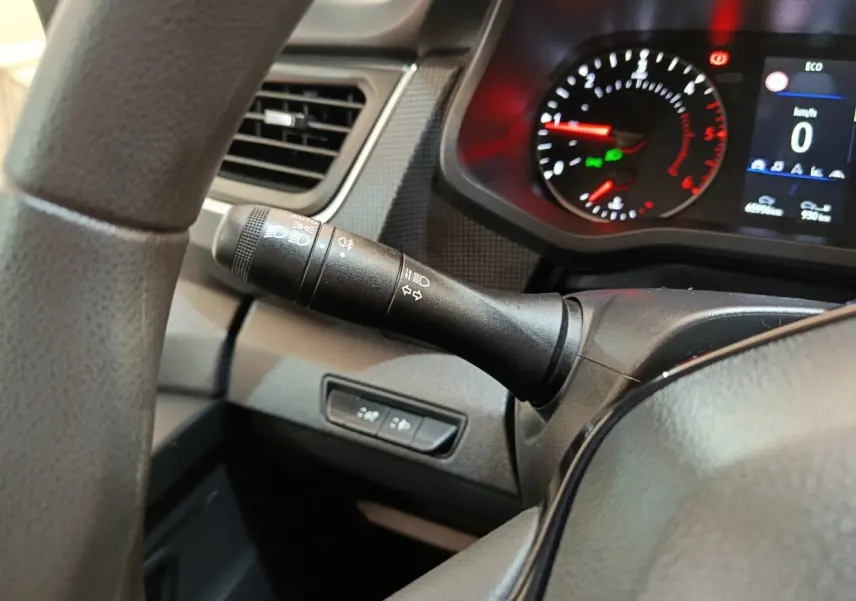 Gros plan sur le commodo gauche et le tableau de bord numérique du Renault Trafic Fourgon blanc, version 2023.