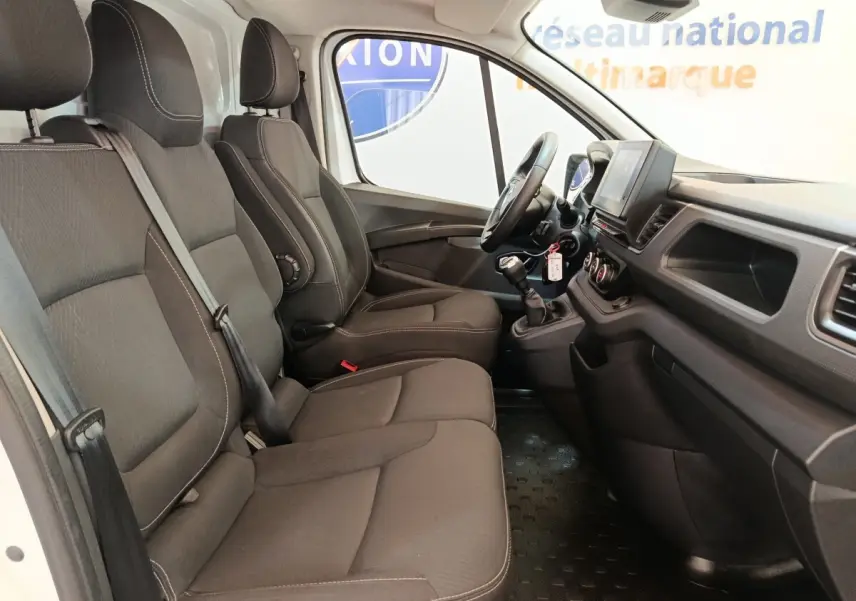 Vue intérieure côté droit du Renault Trafic Fourgon 2023, montrant les sièges noirs et le tableau de bord avec volant multifonctions.