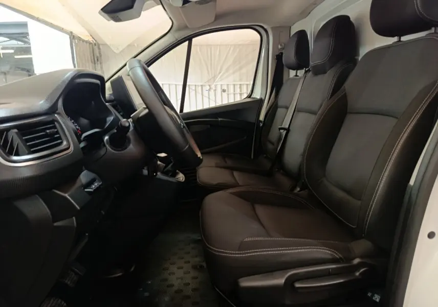Intérieur du Renault Trafic Fourgon 2023, vue côté conducteur, sièges noirs avec volant multifonctions réglable.