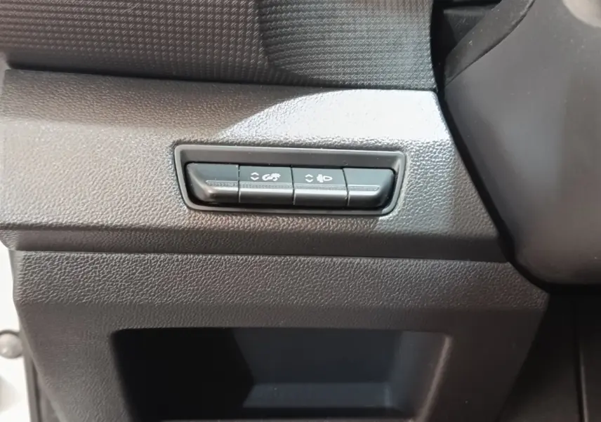 Gros plan sur les boutons de réglage des phares et de l’éclairage intérieur du tableau de bord noir du Renault Trafic Fourgon blanc.