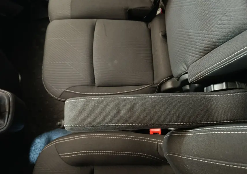 Vue plongeante sur les sièges avant noirs avec accoudoir central du Renault Trafic Fourgon blanc 2023.