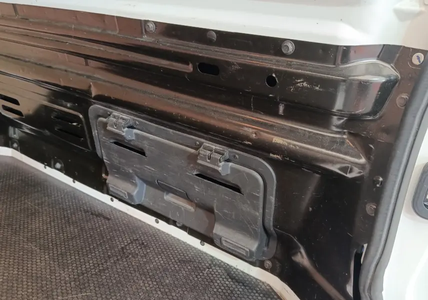 Détail intérieur de la cloison pleine noire du Renault Trafic Fourgon blanc, vue rapprochée côté chargement.