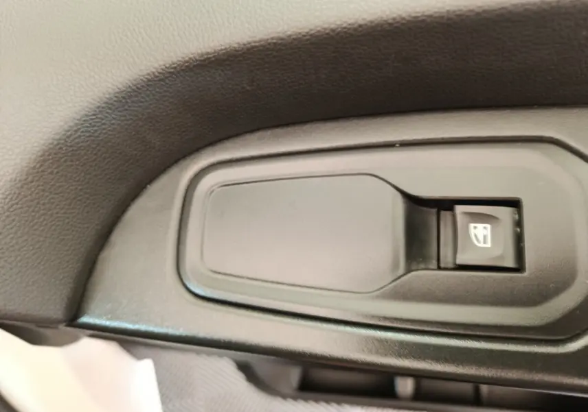 Bouton de commande de lève-vitre électrique sur la porte intérieure d’un Renault Trafic Fourgon blanc.