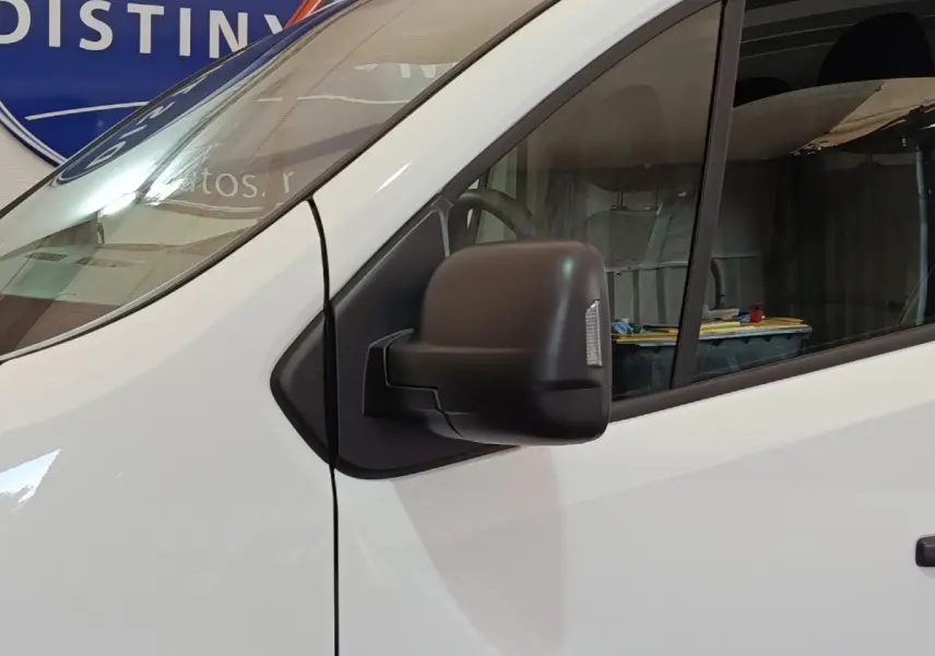 Gros plan sur le rétroviseur noir côté conducteur du Renault Trafic Fourgon blanc, vue latérale avant droite.