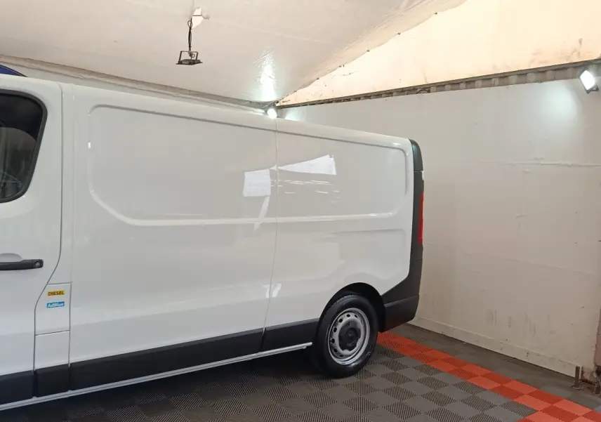 Vue latérale droite d’un Renault Trafic Fourgon blanc 2023 avec jante acier et bandeau noir inférieur.