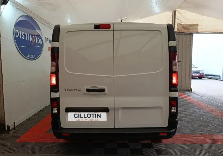 Vue arrière d’un Renault Trafic Fourgon blanc 2023 avec feux allumés dans un garage couvert.