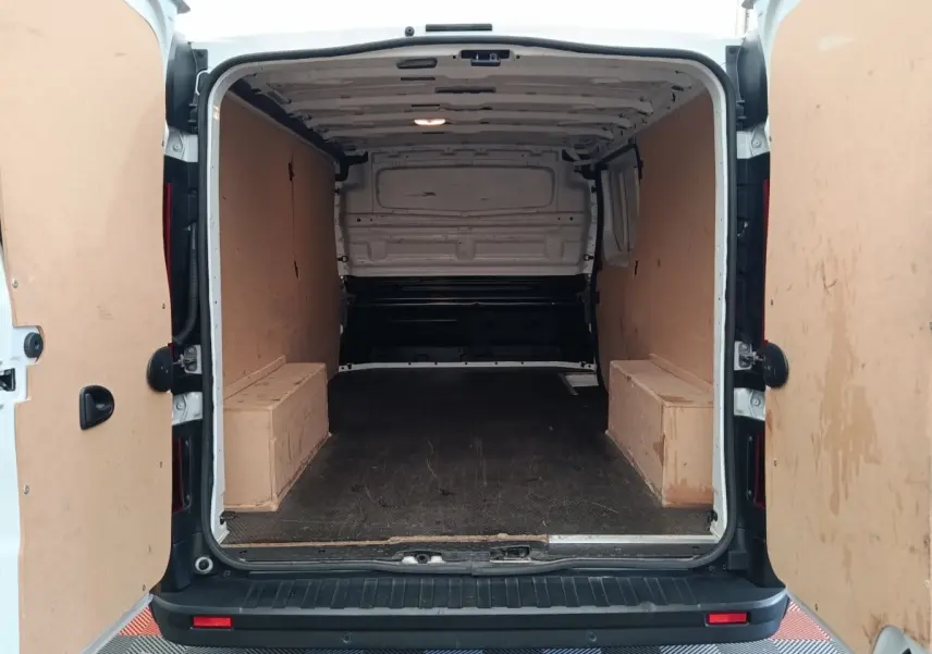 Vue arrière du Renault Trafic Fourgon blanc 2023, montrant l'espace de chargement vide avec cloison pleine en bois.