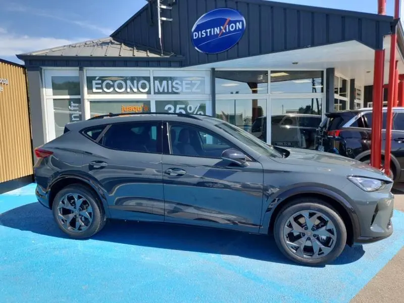 Vue de profil côté gauche du CUPRA Formentor bleu foncé avec jantes alu et lignes dynamiques, stationné devant un showroom.