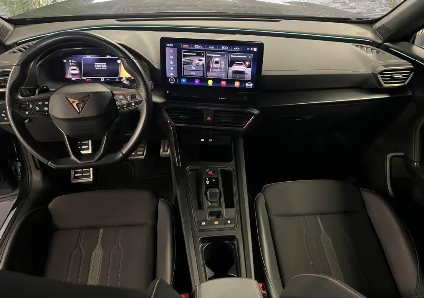 Intérieur avant du CUPRA Formentor 2023, vue du conducteur, tableau de bord noir avec écran tactile central et volant sport cuir.