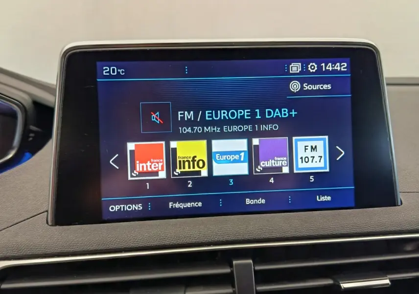 Écran tactile central affichant les stations radio dans l'habitacle du Peugeot 5008 gris foncé, vue intérieure frontale.