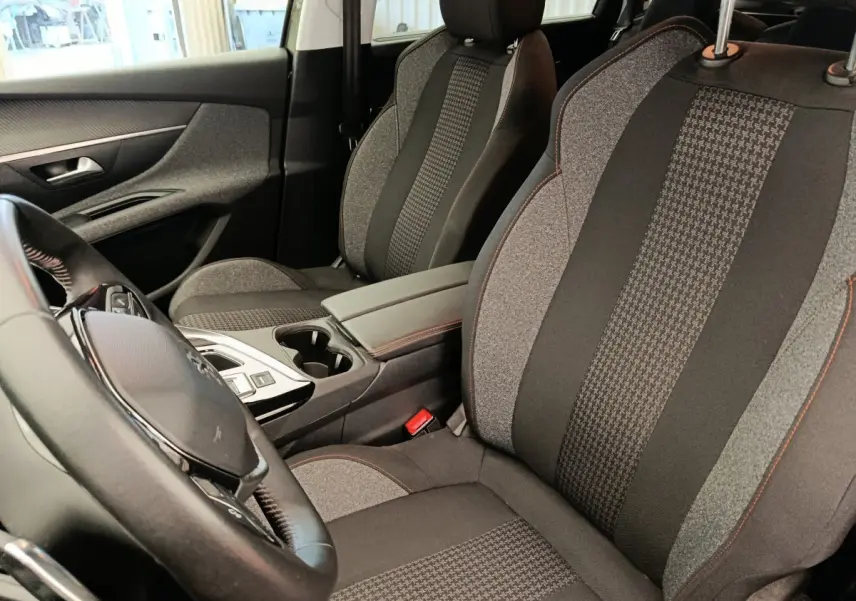 Vue intérieure côté conducteur du Peugeot 5008 2020, sièges tissu gris à motifs et volant cuir noir.