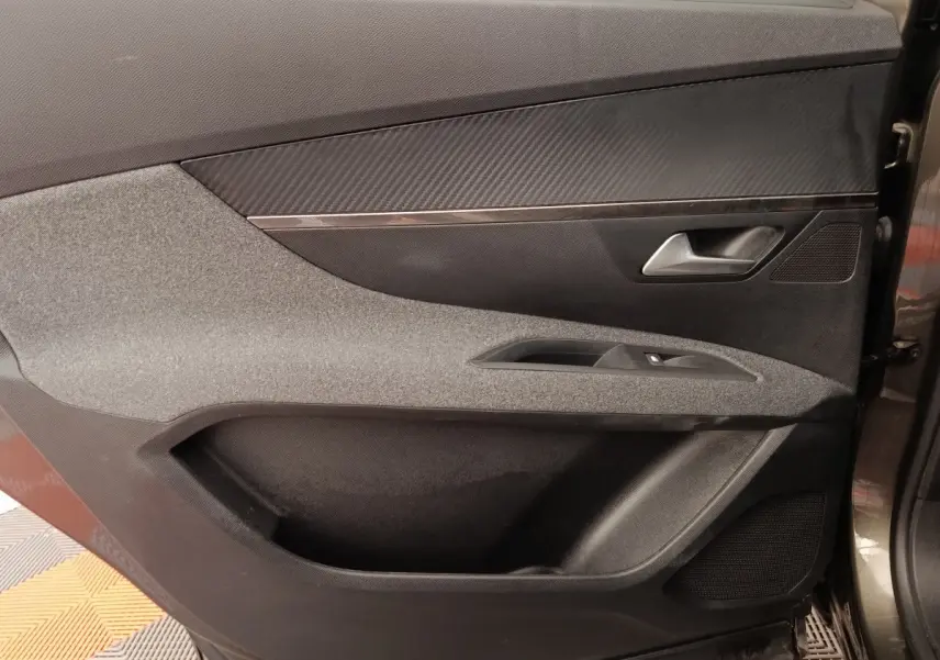 Vue intérieure côté droit de la porte avant grise du Peugeot 5008 avec habillage tissu et plastique noir.