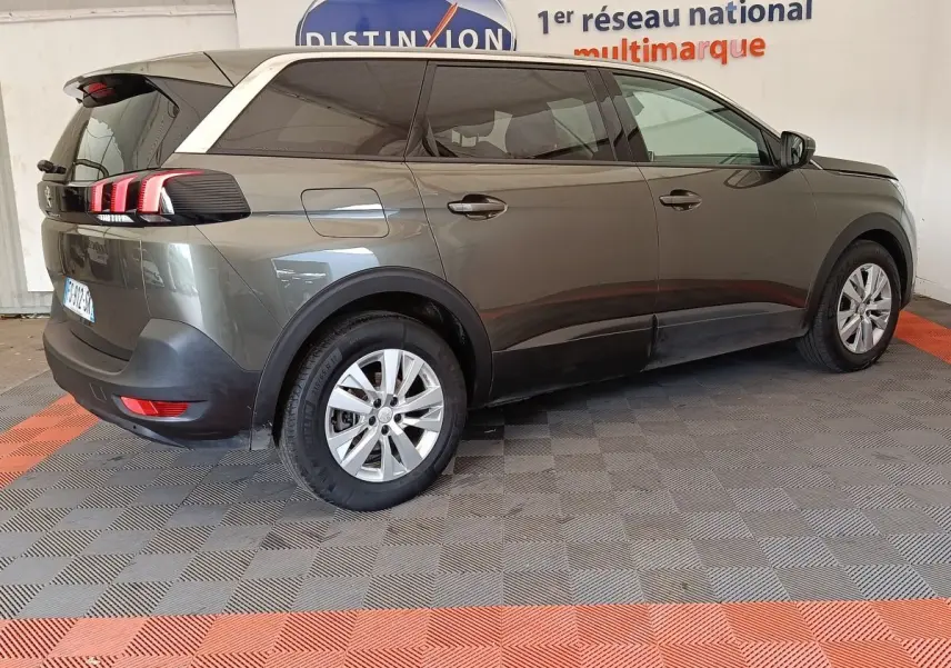 Peugeot 5008 gris foncé en vue 3/4 arrière droit, avec feux arrière à griffes rouges distinctifs.