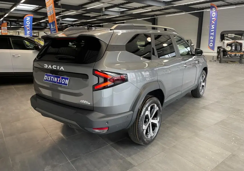 Vue 3/4 arrière droite du Dacia Bigster gris schiste avec feux arrière en forme de flèche et jantes alliage 18 pouces diamantées.