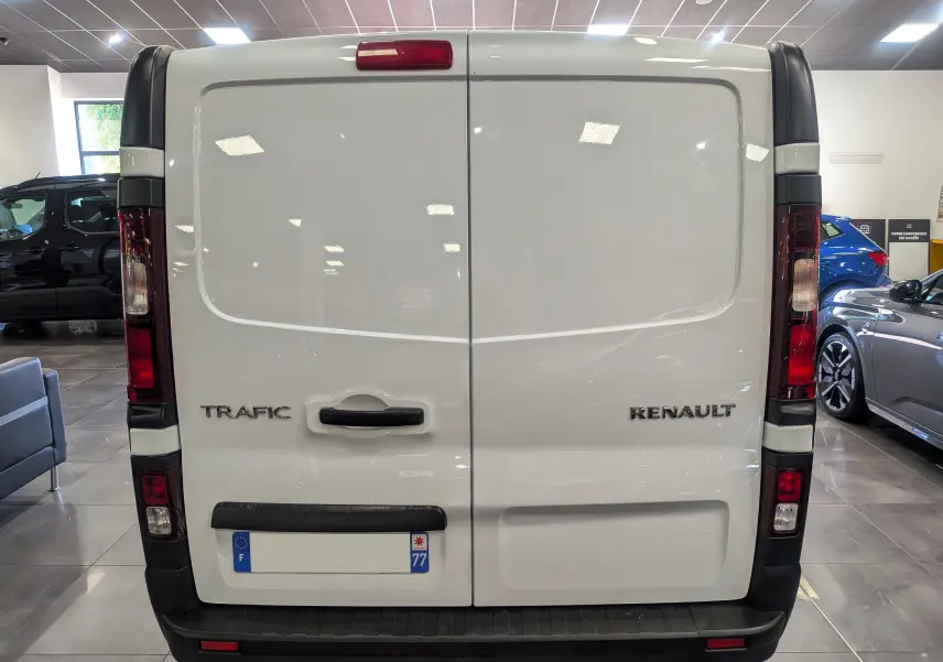 Vue arrière d’un Renault Trafic Fourgon blanc minéral 2024, portes battantes fermées avec logo et plaque d’immatriculation visible.