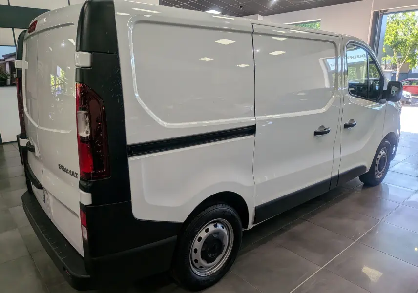 Vue 3/4 arrière droite du Renault Trafic Fourgon blanc minéral 2024 avec porte latérale coulissante et feux arrière verticaux.