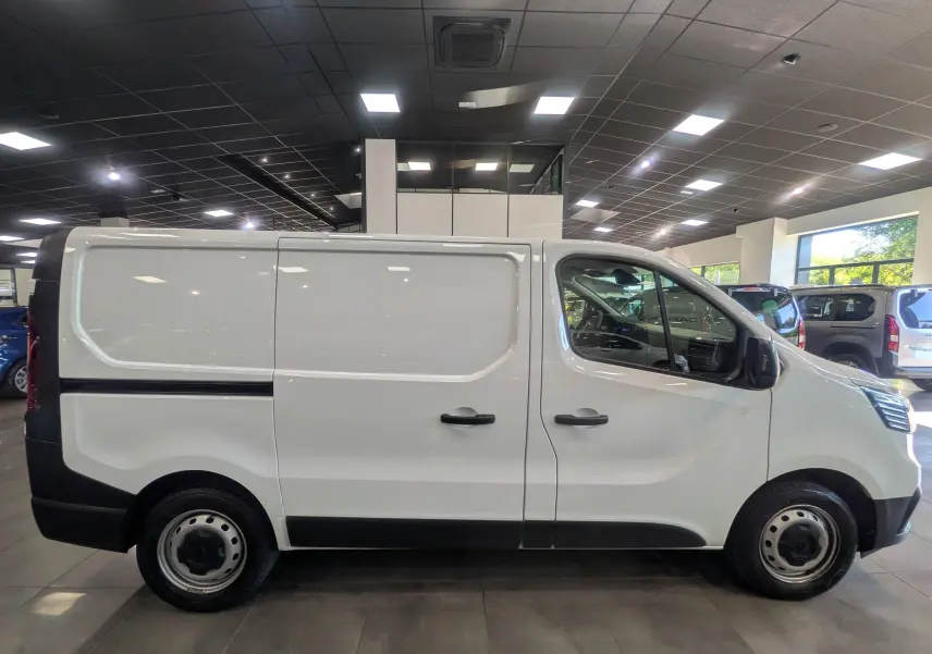 Vue de profil côté droit du Renault Trafic Fourgon blanc minéral 2024 avec portes latérales et jantes acier noires.