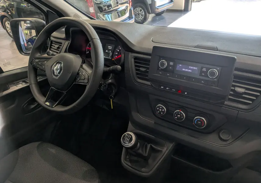 Vue intérieure côté conducteur du Renault Trafic Fourgon 2024, tableau de bord noir avec volant multifonction et levier de vitesse manuel.