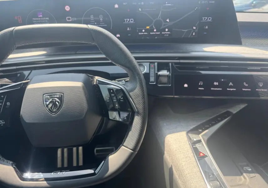 Vue intérieure centrée sur le volant noir du Peugeot 3008 Hybrid GT avec cockpit numérique et commandes tactiles.