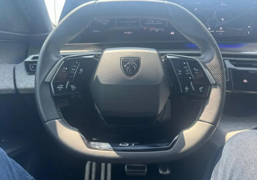 Vue rapprochée du volant noir du Peugeot 3008 Hybrid 145 e-DCS6 GT avec commandes intégrées et logo central GT.