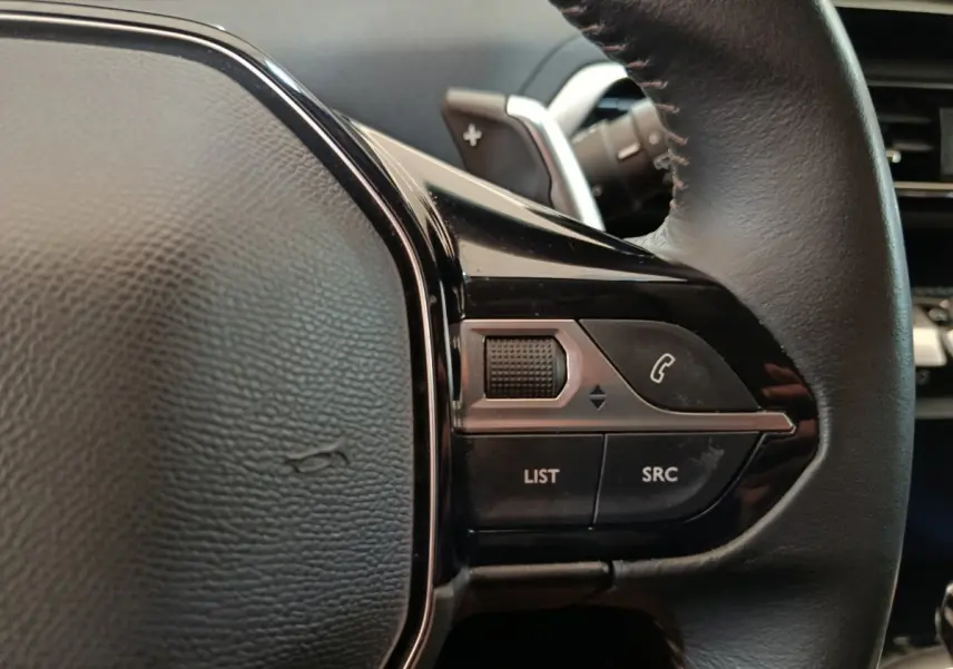 Gros plan sur la partie droite du volant cuir noir du Peugeot 3008 2022 avec commandes audio et téléphone intégrées.