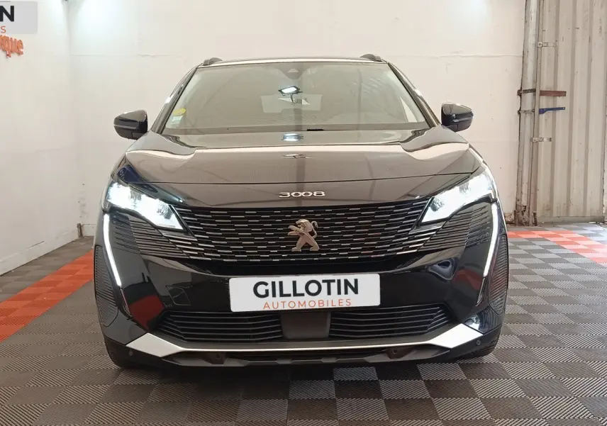 Vue frontale d'un Peugeot 3008 noir 2022 avec feux LED allumés et calandre distinctive en intérieur showroom.