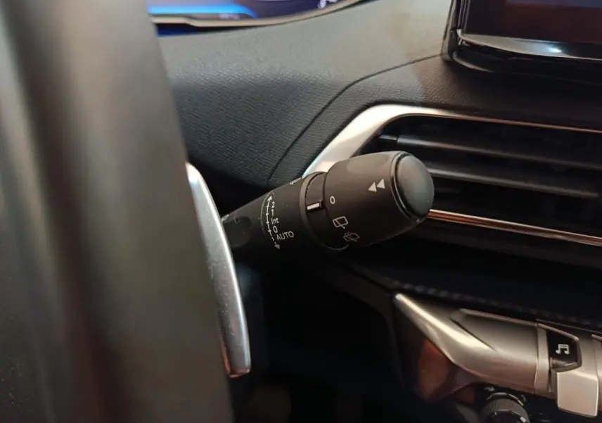 Gros plan sur la commande des essuie-glaces à gauche du volant dans l’habitacle noir du Peugeot 3008 2022.