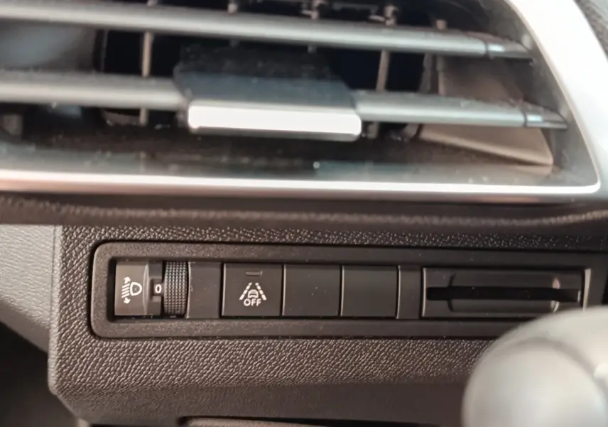 Détail du tableau de bord noir du Peugeot 3008 2022, avec commandes d'éclairage et aide à la conduite visibles.