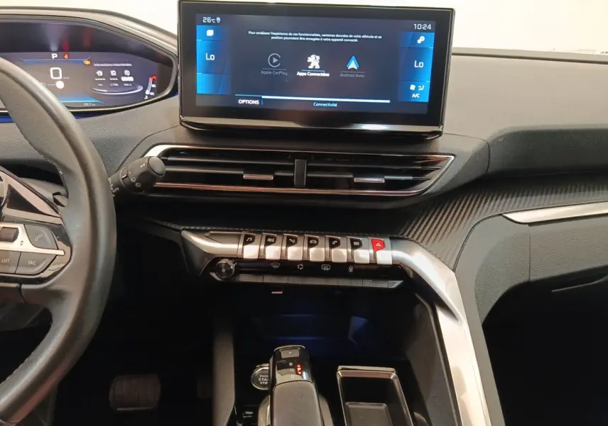 Vue intérieure centrée sur la console et l’écran tactile du Peugeot 3008 noir, avec commandes piano et volant partiel visible à gauche.
