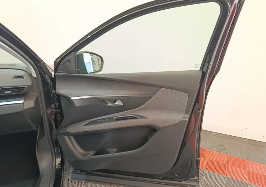 Vue intérieure côté gauche de la porte avant noire du Peugeot 3008 2022, avec garniture tissu et plastique gris.