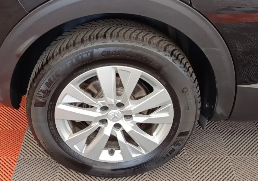Gros plan sur la roue avant droite du Peugeot 3008 noir, mettant en valeur la jante alu et le pneu Michelin CrossClimate 2.