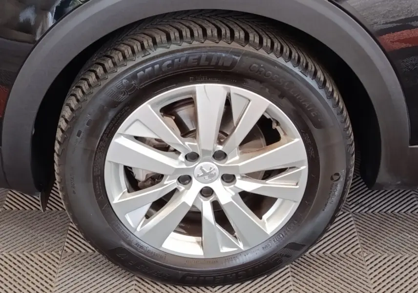 Gros plan sur la roue avant droite du Peugeot 3008 noir, jante alliage argent avec pneu Michelin CrossClimate.