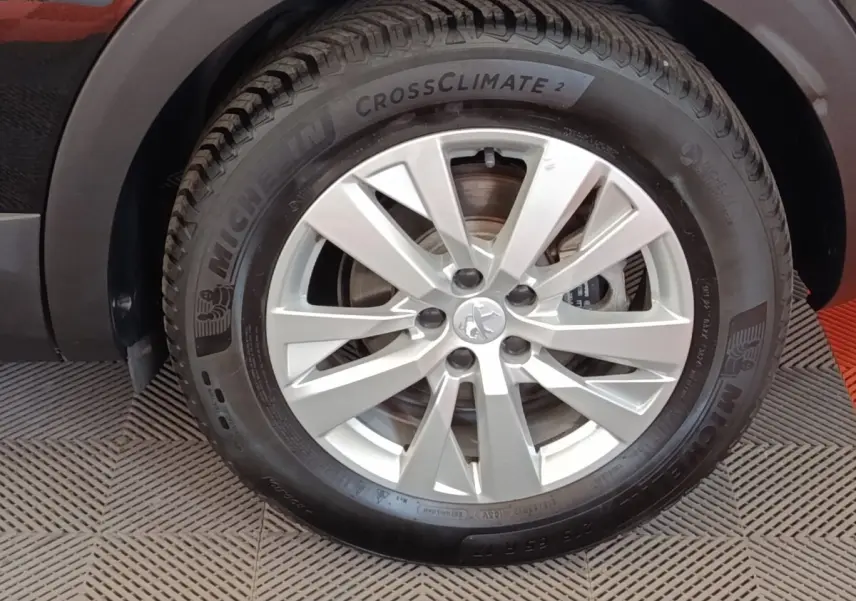 Gros plan sur la roue avant gauche d’un Peugeot 3008 noir, jante alliage argentée et pneu Michelin CrossClimate 2.
